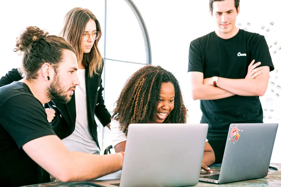 Team um den Schreibtisch mit Blick auf zwei Laptops