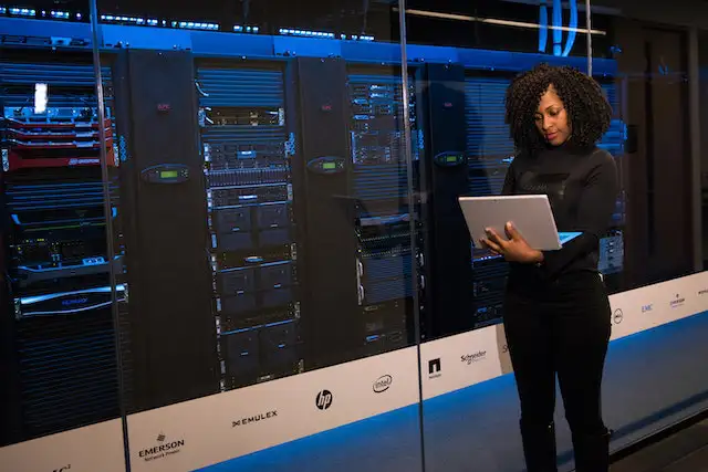 Woman with laptop in front of servers